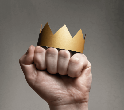 Hand gripping a gold paper crown against a textured background